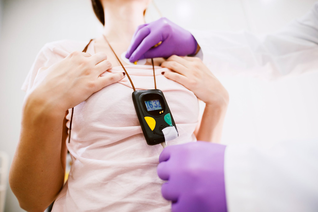 A healthcare professional wearing purple gloves adjusts a medical device on a patient.