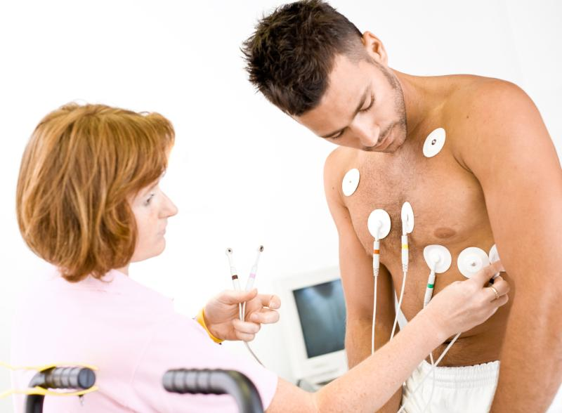 A healthcare professional attaches electrodes to a man's chest for a medical test.